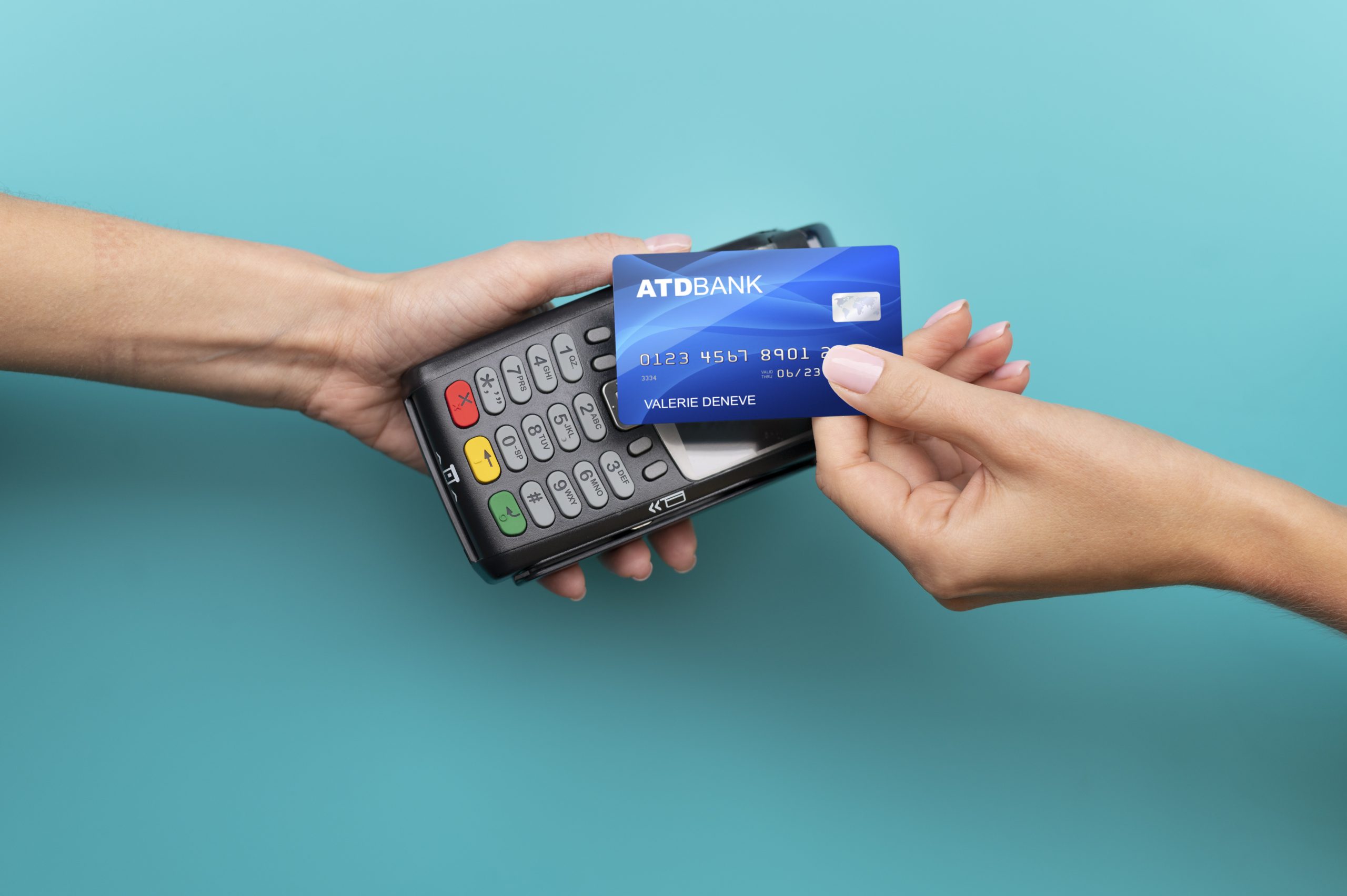 A person holding a contactless payment terminal while another hand presents a blue credit card from ATD Bank, ready for a tap-to-pay transaction.