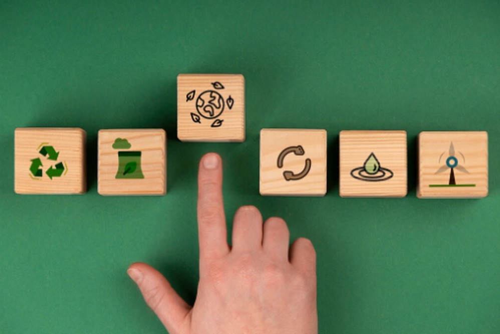 A hand points to a wooden block with an eco-friendly Earth icon, surrounded by other blocks showing sustainability symbols, representing ESG funds and environmental responsibility.